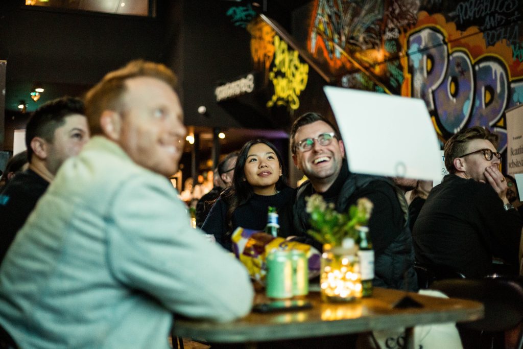 People sitting at table smiling at presenter 