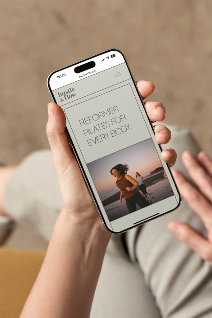 Hand holding phone with screen showing Hustle & Flow's website